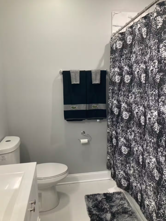 Clean white bathroom with folded navy towels and a patterned shower curtain