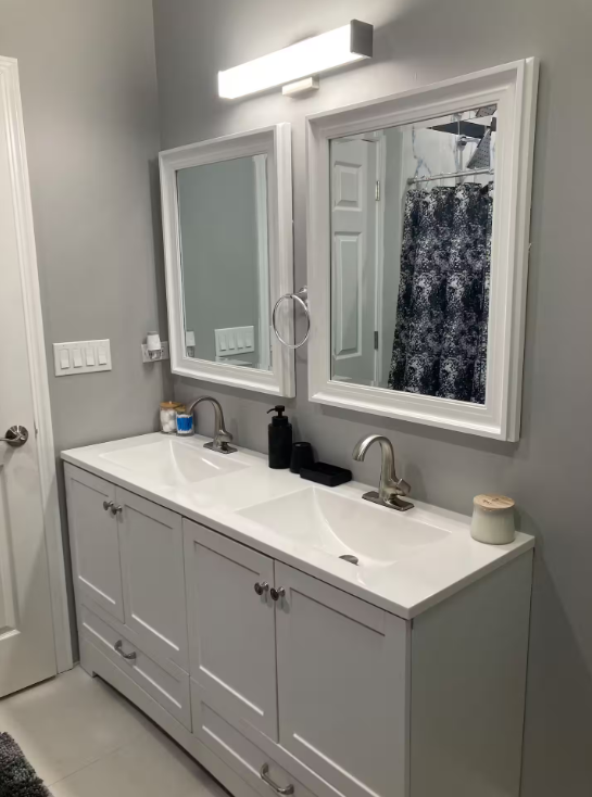 Bright double vanity bathroom with white cabinets, two mirrors and modern fixtures