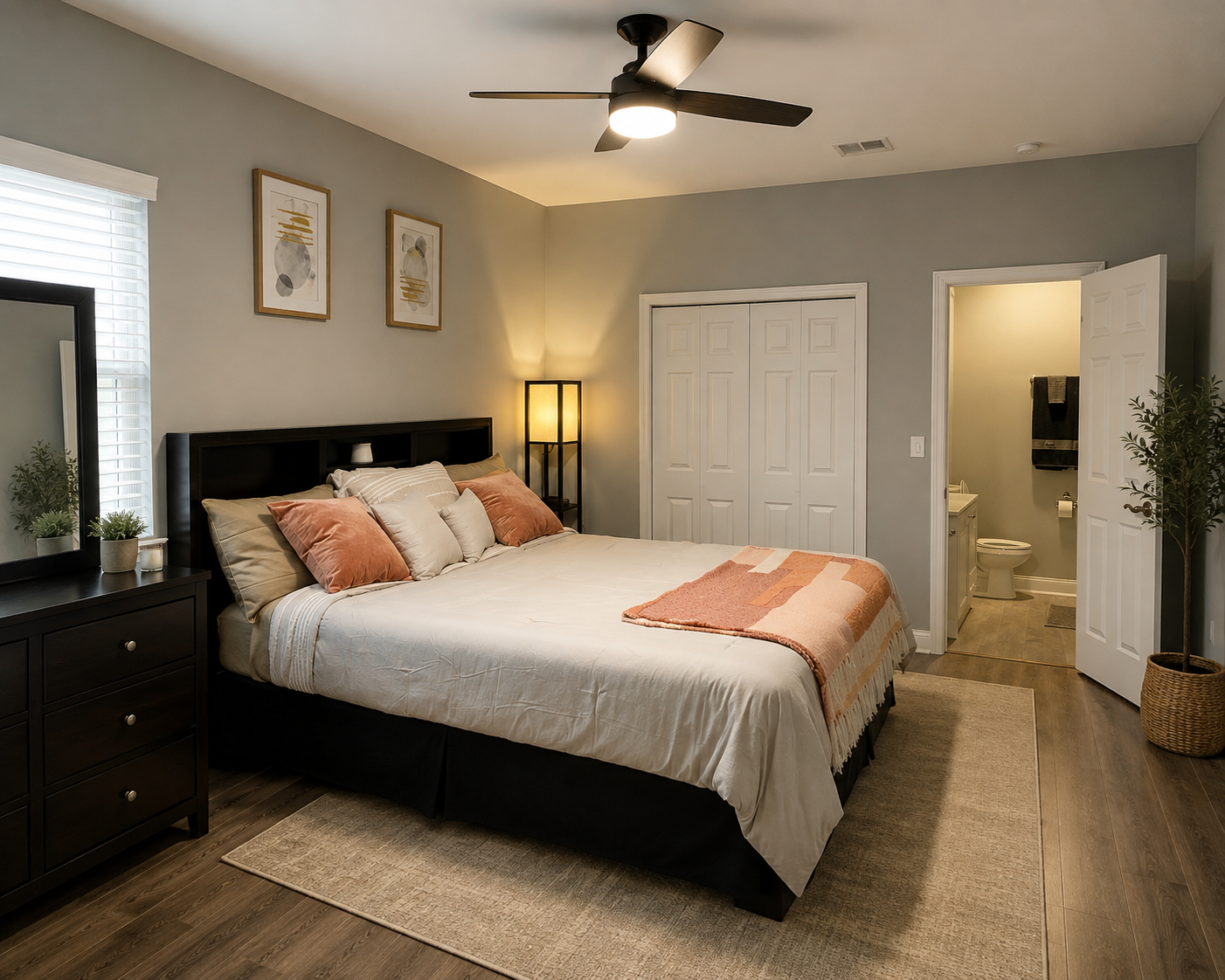 Bedroom with dark wood bed frame, white bedding and view into the en-suite bathroom