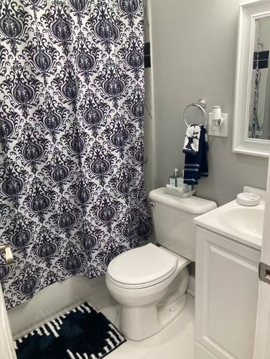 White bathroom with a navy patterned shower curtain and matching towels