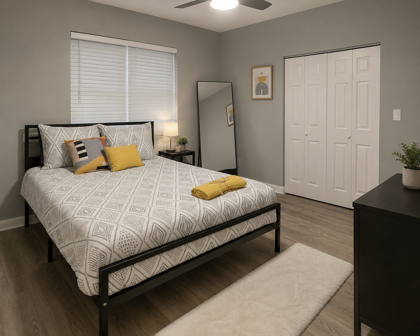 Bright guest bedroom with patterned bedding, yellow accent pillows and a white shag rug